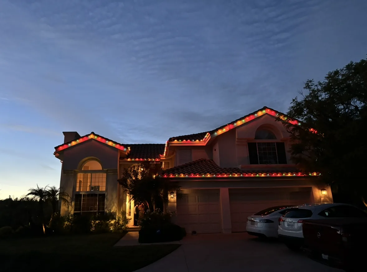 Two-story home outlined in red and warm white C9 Christmas lights