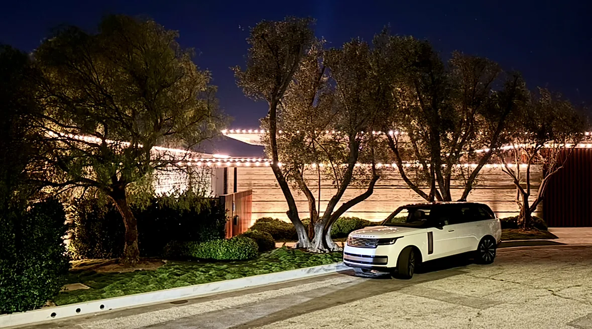 Professional holiday lighting: roofline Christmas lighting framed by trees at night