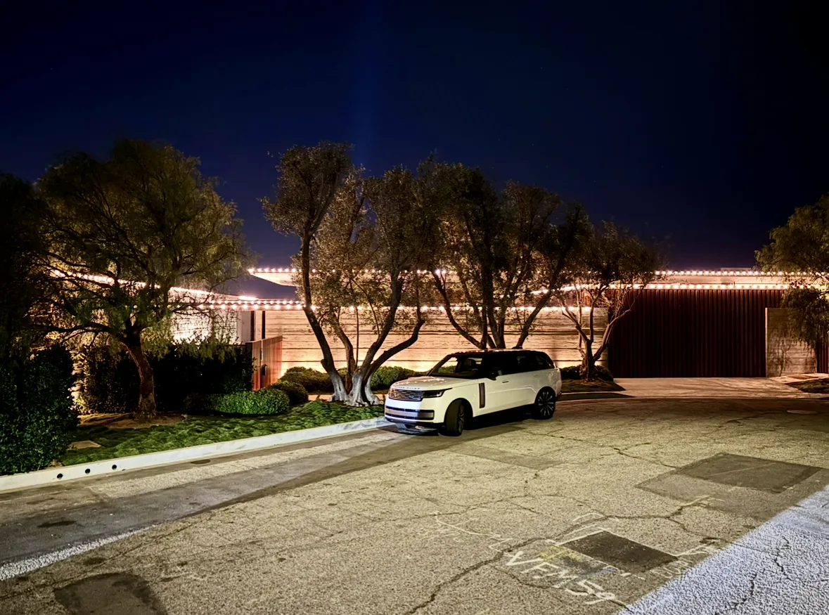 Commercial Christmas lighting in Houston: single-story home with warm white roofline lights behind mature trees