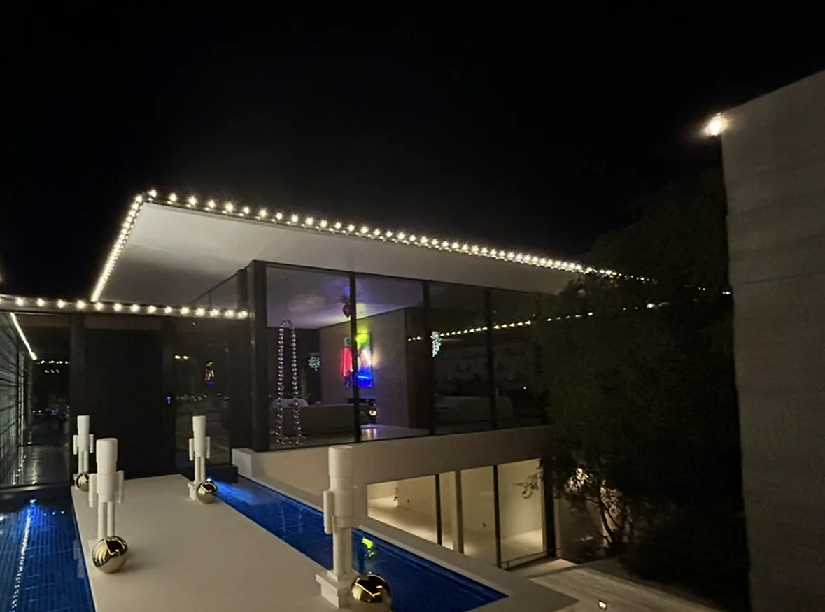 Permanent app-controlled holiday lighting: warm white Christmas lights along a modern roofline and wall