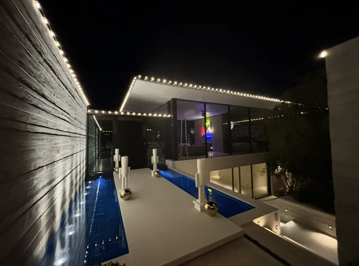 Professional holiday lighting: modern home and pool courtyard outlined in warm white Christmas lights